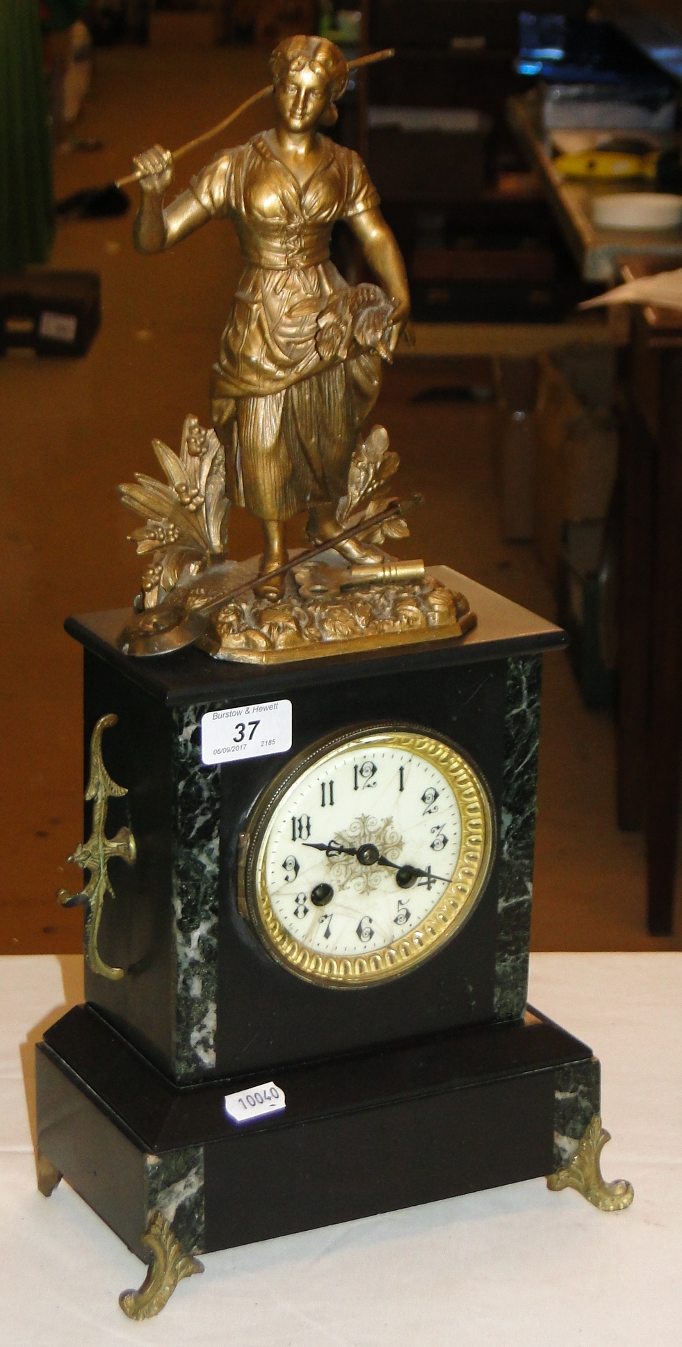 A slate and marble mantel clock surmounted by a gilded spelter figure.