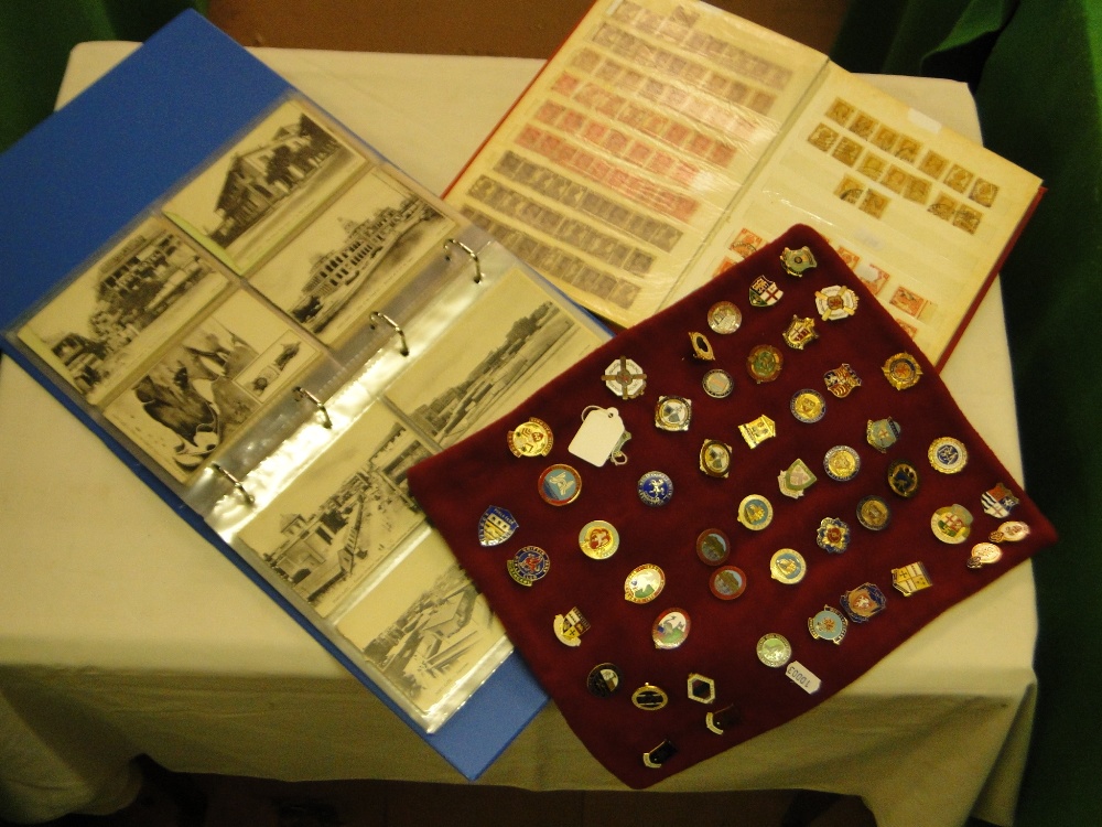 Album of postcards, postage stamp album and a display of badges.