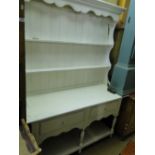A white painted pine dresser with open plate rack, drawers and pot board below.