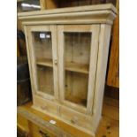 A small hanging pine cabinet with glazed doors.
