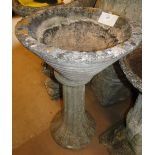 A weathered concrete garden planter on pedestal.