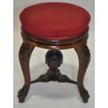 A Victorian carved walnut revolving music stool on cabriole legs.