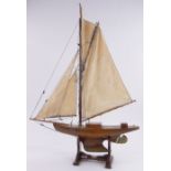 A Vintage wooden hulled pond yacht, with sails and rigging on wooden stand, overall height 98cm,