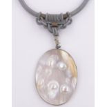 An Oriental nature pearl disc pendant on silk cord, pendant height 65mm.