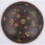 A small Middle Eastern leather shield, with painted designs and metal bosses, diameter 32cm.