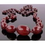 A long string of graduated cherry amber beads, largest bead 30mm x 22mm, gross weight 85g.