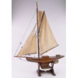 A Vintage wooden hulled pond yacht, with sails and rigging on wooden stand, overall height 98cm,