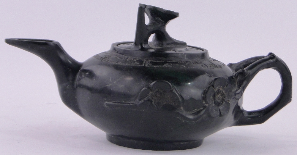 An Oriental relief carved black stone teapot, with carved floral knop, length 17cm.