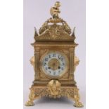 A 19th century ornate French cast brass cased mantel clock, surmounted by a musical cherub,