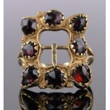 An 18ct gold facet-cut garnet set buckle ring, panel height 21mm, size M.