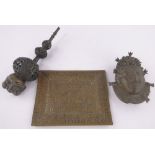 An African bronze mask, height 20cm, an embossed brass plaque and bronze pipe, (3).