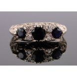 An 18ct gold 7 stone sapphire and diamond ring, carved and pierced shoulders, size M.