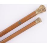 2 Victorian Malacca walking canes with ornate unmarked relief embossed gilt metal tops.