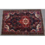 Hamadan woollen rug, deep blue field centred with a red reserve with fawn spandrels, size approx.