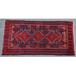 Baluchi woollen rug, red lozenge form pole medallion against a deep blue field,