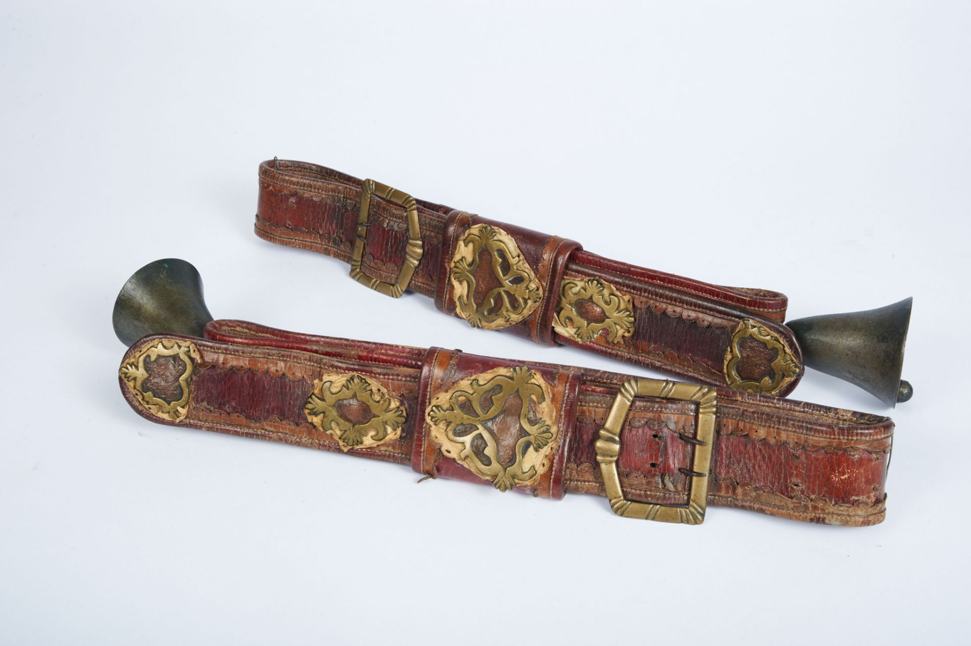 A Pair of cattle Belts with Bells, leather and yellow metal applications "Cartouches", European,