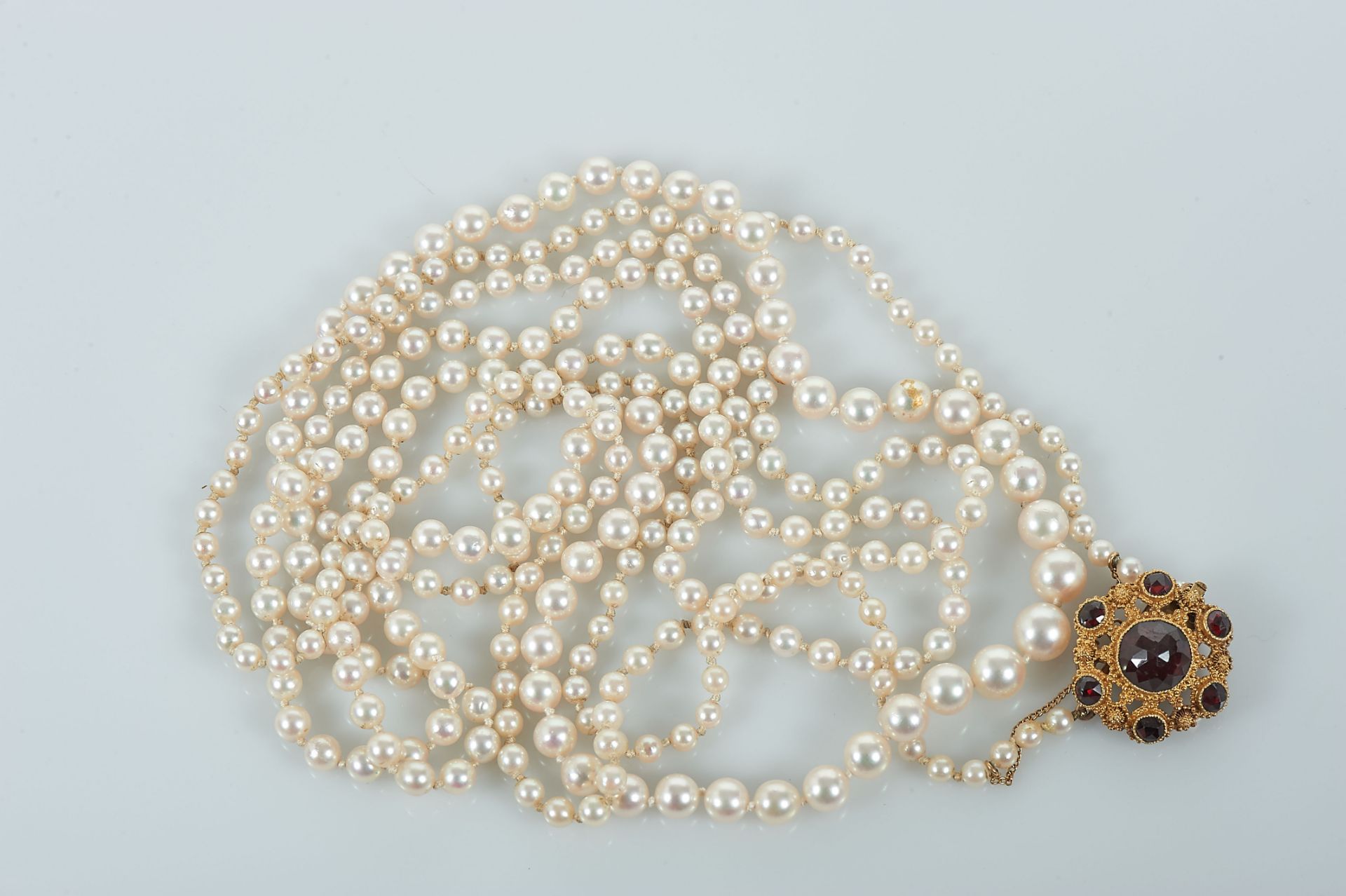 A Necklace, string of degradée culture pearls, gold clasp set with garnets, European, 20th C. (mid), - Bild 2 aus 3