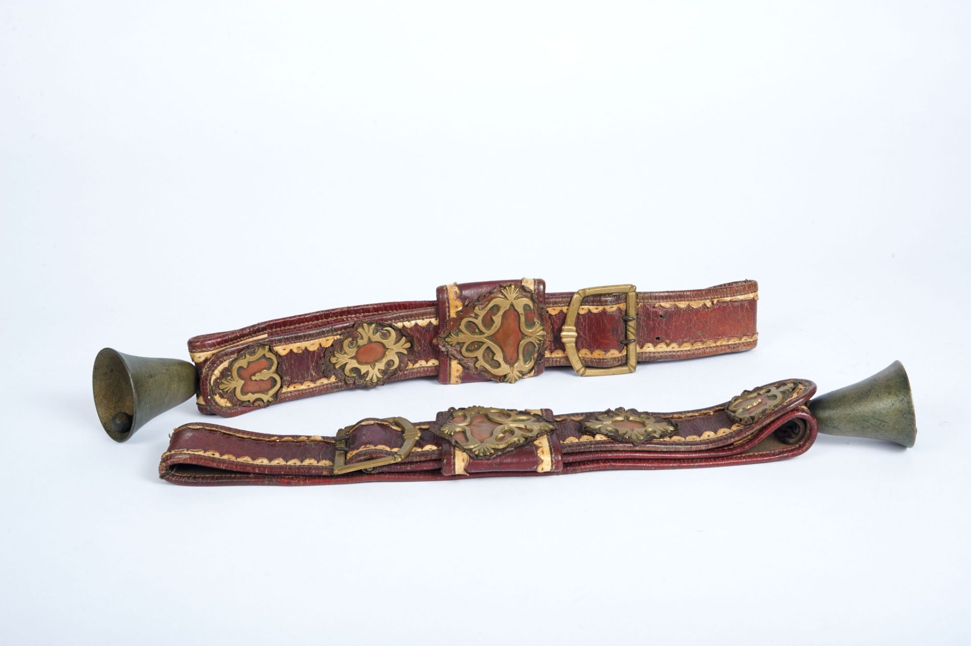 A Pair of Cattle Belts with Bells, leather and yellow metal applications "Cartouches", European,