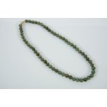 A Necklace, a string of 56 Jadeite beads (9 mm), gadrooned 14 kt. gold clasp, marked, Dim. - 57,5