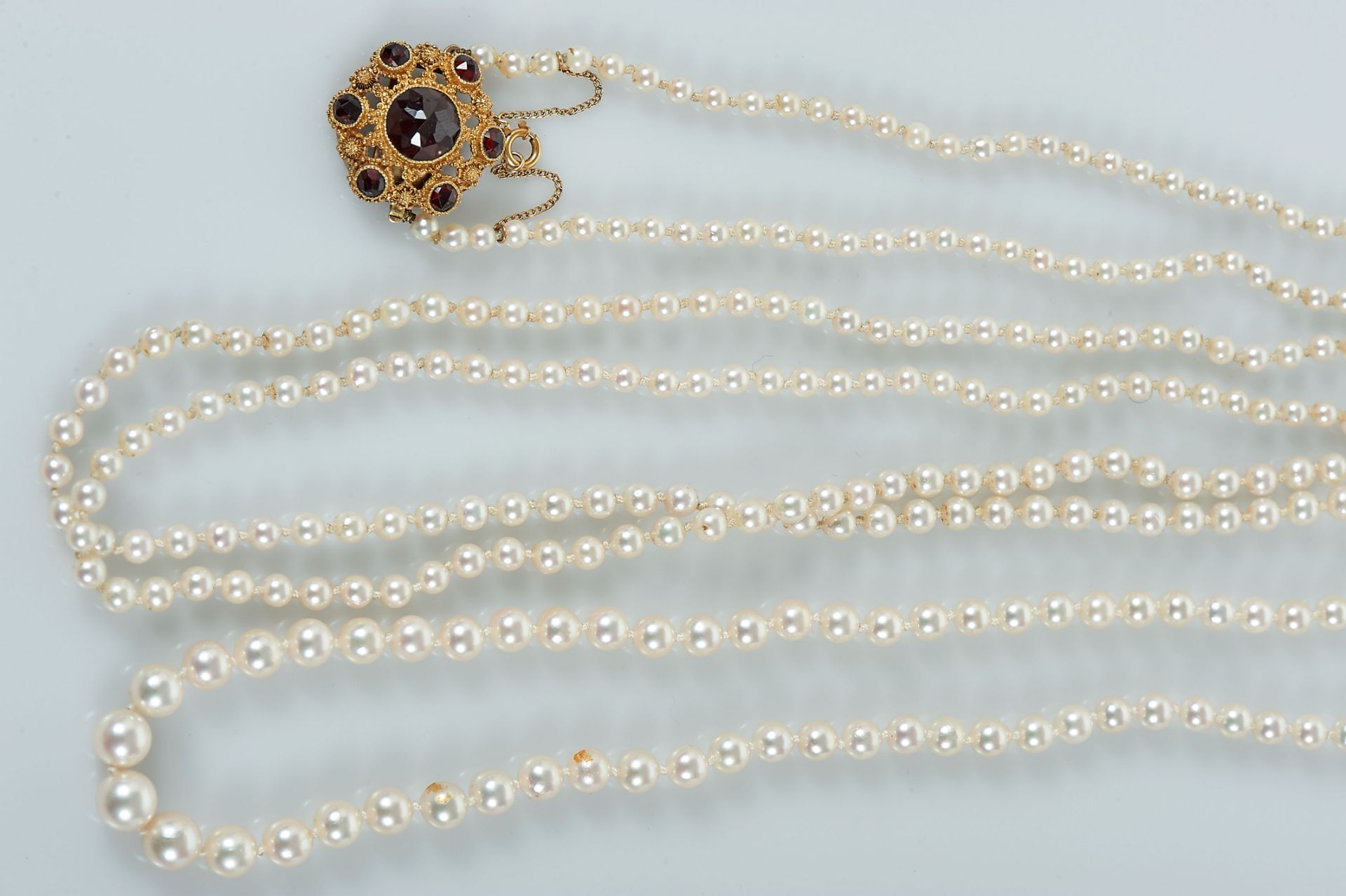 A Necklace, string of degradée culture pearls, gold clasp set with garnets, European, 20th C. (mid), - Bild 3 aus 3