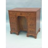 A George III mahogany kneehole desk, arrangement of eight drawers and central cupboard, brass swan-