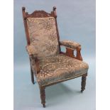 A pair of late Victorian walnut drawing room armchairs, with carved scroll crestings, front turned