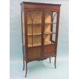 An Edwardian inlaid mahogany display cabinet, lined interior with two shelves, enclosed by a pair of