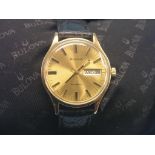 A gentleman's Bulova 9ct. gold wristwatch, champagne day-date dial with baton markers, black leather