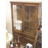 A period-style dark oak display cabinet, pair of leaded glass doors enclosing two shelves,