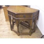 A period-style oak side table with drop-leaf, angled form with three frieze drawers, on baluster-