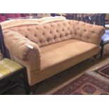 An early 20th century two-seater Chesterfield settee, upholstered in a buttoned peach dralon, on