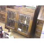 A pair of dark oak wall cabinets, each enclosed by a pair of leaded glass doors, 2ft. 10in.