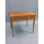 A Victorian writing table, pine with ash top, two frieze drawers, on turned legs with casters,
