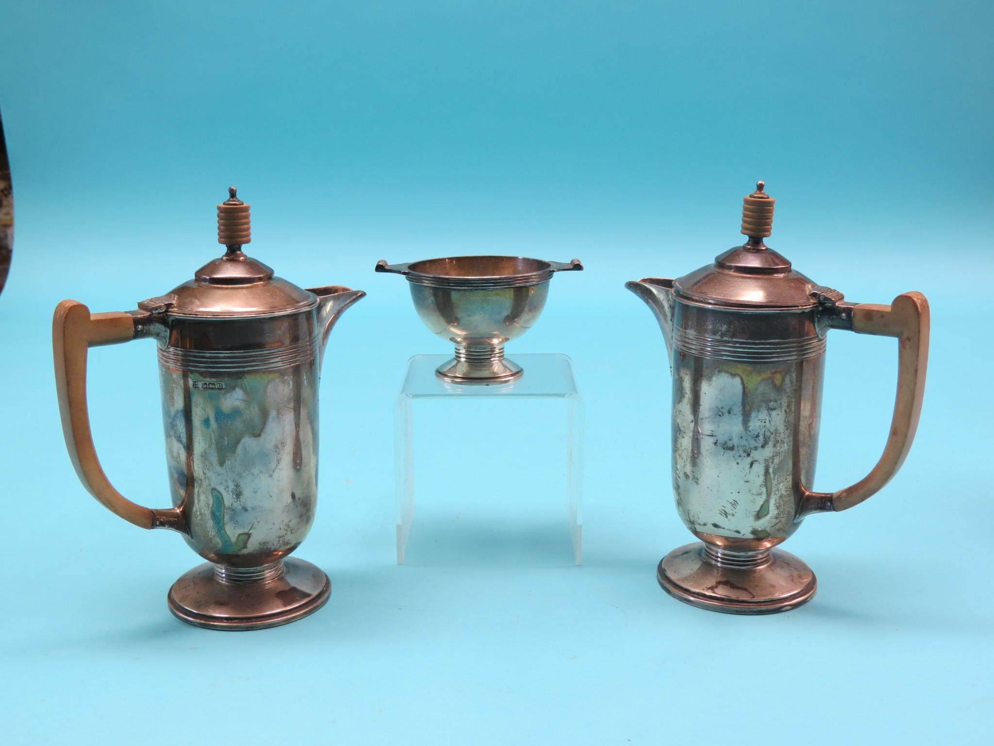 An Art Deco silver three-piece coffee set, two coffee pots, each with wood handle and finial, and