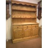 A waxed pine dresser, twin-shelf plate rack with five short drawers, panelled cupboard base with