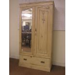 A Victorian stripped pine wardrobe, hanging space enclosed by two doors, one with inset bevelled