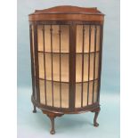 A George V mahogany display cabinet, half-round form with twin-shelf lined interior enclosed by