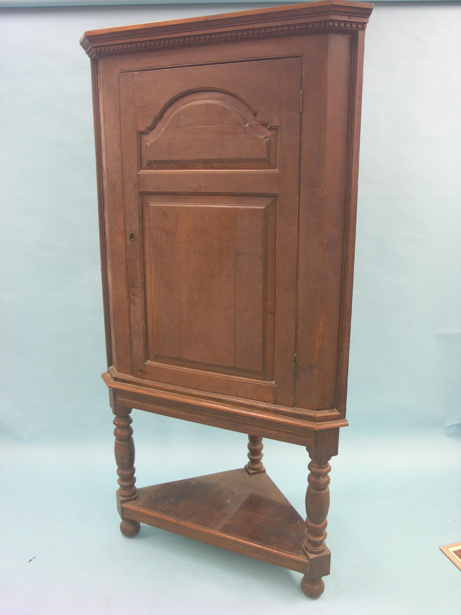 A large George II oak corner cupboard, door with fielded panels, two shaped shelves enclosed and