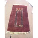 An eastern wool prayer rug, predominantly in red, black and cream, 5ft. x 3ft., a similar runner,