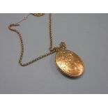 A 9ct. engraved gold locket, 20 grams, on a yellow metal link chain