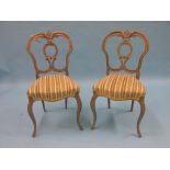A pair of Victorian bleached rosewood dining chairs, double-scroll backs and upholstered seats, on