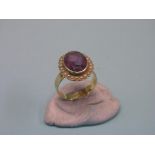 A gold dress ring, set large central amethyst and surrounding seed-pearls, size Q