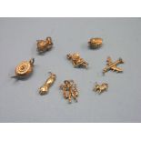 Seven 9ct. gold charms, 14.3 grams total and a yellow metal charm in the form of a forearm