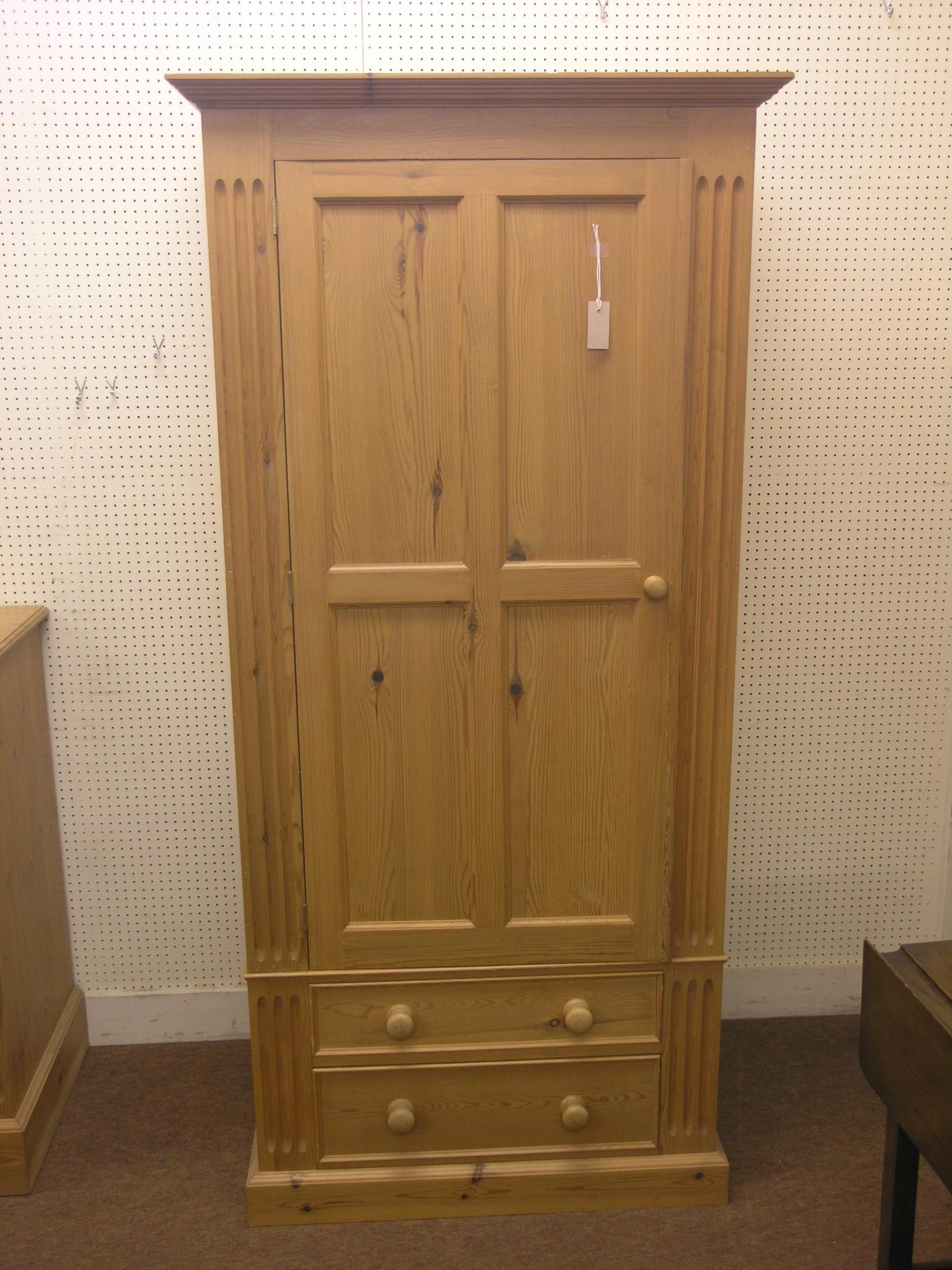 A solid, waxed pine wardrobe, panelled door enclosing space for hanging, two drawers beneath, 2ft.