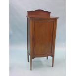 An Edwardian inlaid mahogany music cupboard, bow-fronted panelled door enclosing three shelves, 1ft.