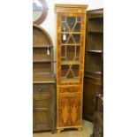 A narrow, period-style yew-veneered bookcase, astragal-glazed door above single drawer and cupboard,