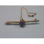 A 9ct. gold bar brooch, claw-set diamond chips and central blue stone