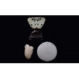 Three carved and fretworked white jades: a small fruit with an animal, a "butterfly" [...]