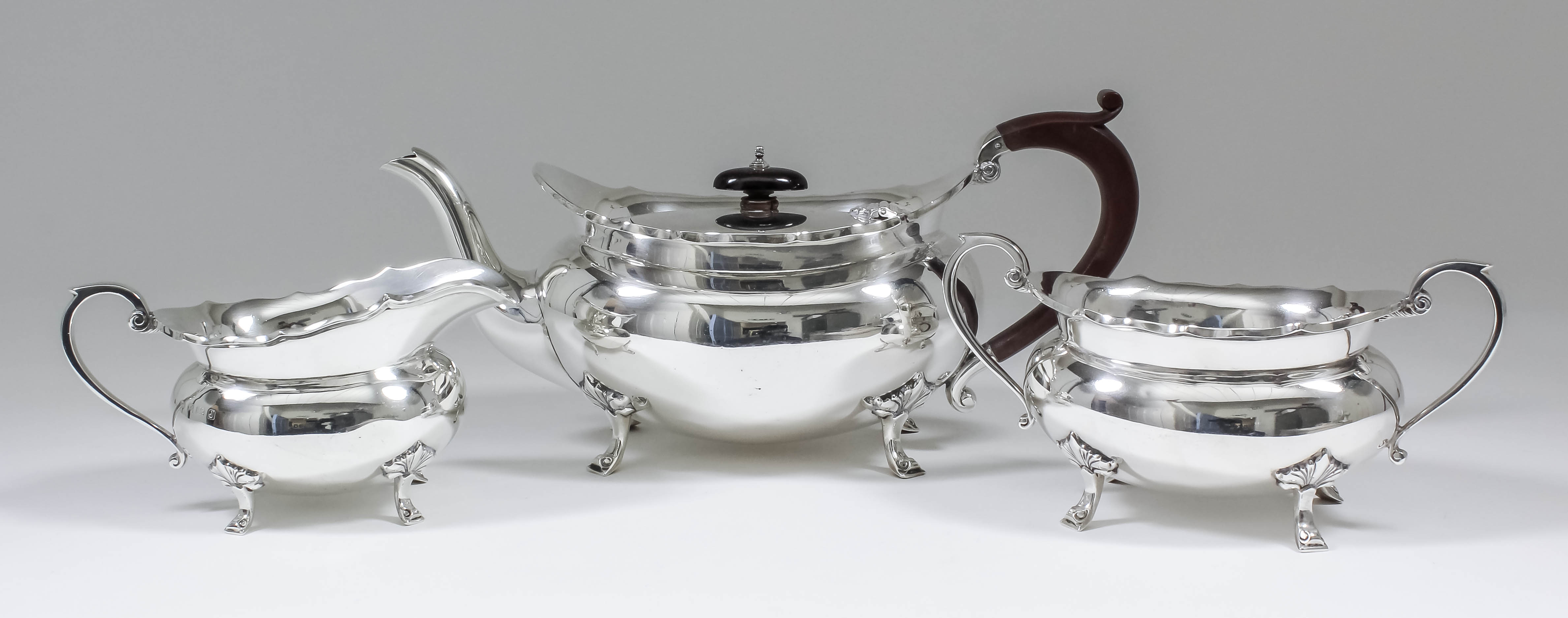 A George V silver oval three piece tea service, the plain squat bodies with shaped rims, C-scroll