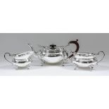 A George V silver oval three piece tea service, the plain squat bodies with shaped rims, C-scroll